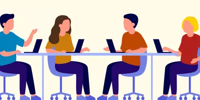 Vier Studenten sitzen mit Laptops am Schreibtisch.