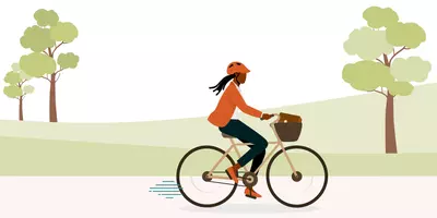 Eine Frau fährt auf einem Fahrrad. Im Hintergrund sind Hügel und Bäume zu sehen.