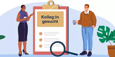 Zwei Mitarbeiter neben großem Klemmbrett mit Aufschrift "Kolleg:in gesucht"