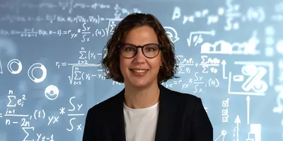 Eine Frau mit Brille befindet sich im Vordergrund. Im Hintergrund sieht man Formeln, Rechnungen und Zahlen.