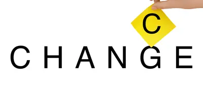 Schriftzug mit dem Wort "Change" vor weißem Hintergrund. Eine Hand hält den gelb unterlegten Buchstaben "C" über das "G" im Schriftzug, sodass aus "Change" "Chance" wird.