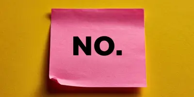 Auf dem Bild ist ein pinker Post-It vor gelbem Hintergrund zu sehen. Der Post-It trägt die Aufschrift "NO".