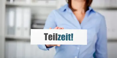 Zu sehen ist eine Frau in Büroumgebung, die ein Stück Papier mit der Aufschrift "Teilzeit" in der Hand hält.